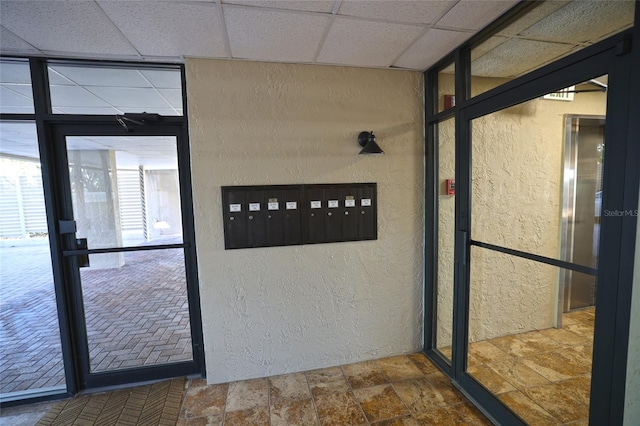 interior space with a paneled ceiling and a mail area