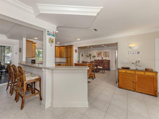 kitchen featuring recessed lighting, a peninsula, visible vents, a kitchen breakfast bar, and ornamental molding