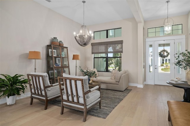 sitting room with a high ceiling, baseboards, an inviting chandelier, and wood finished floors