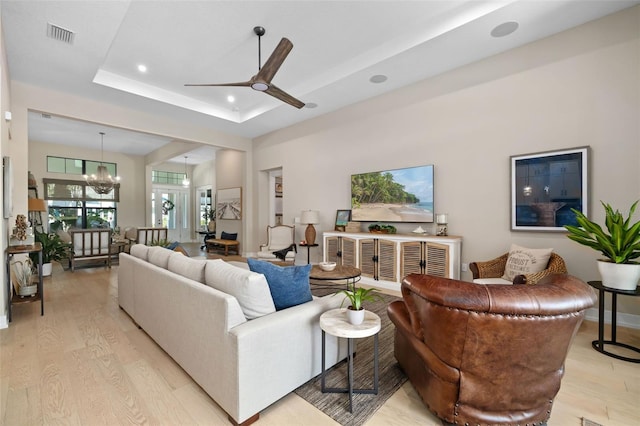 living room featuring a tray ceiling, visible vents, light wood-style flooring, and recessed lighting