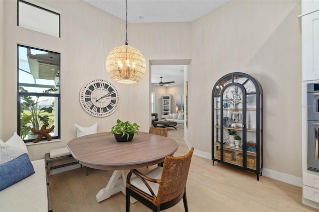 dining space featuring an inviting chandelier, light wood-style flooring, and baseboards