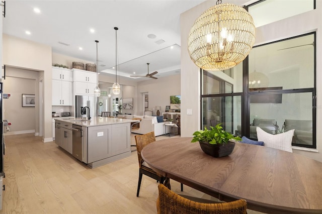 dining area featuring recessed lighting, ceiling fan with notable chandelier, visible vents, light wood-type flooring, and a tray ceiling