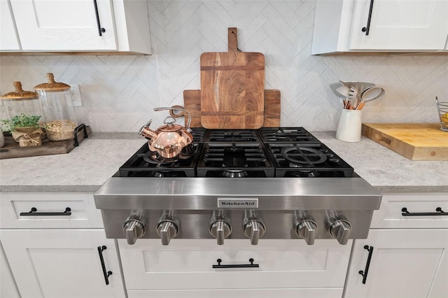 room details with light stone counters, white cabinets, stainless steel gas cooktop, and decorative backsplash