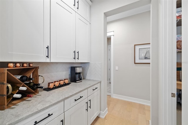 bar with tasteful backsplash, light wood-type flooring, and baseboards