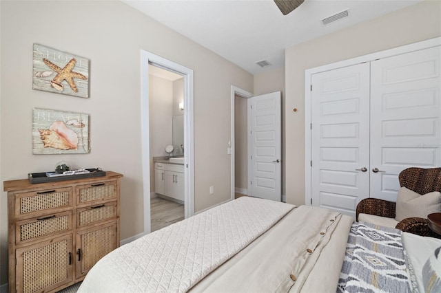 bedroom featuring baseboards, ensuite bath, visible vents, and a closet