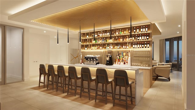 bar with light tile patterned floors and a tray ceiling