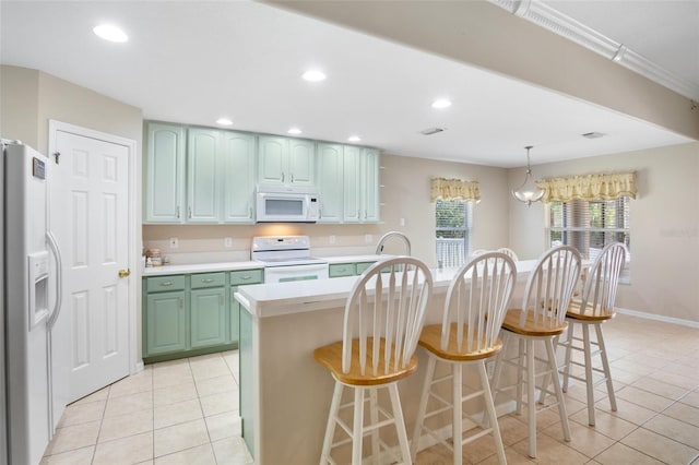 kitchen with light tile patterned flooring, green cabinetry, a kitchen breakfast bar, pendant lighting, and white appliances