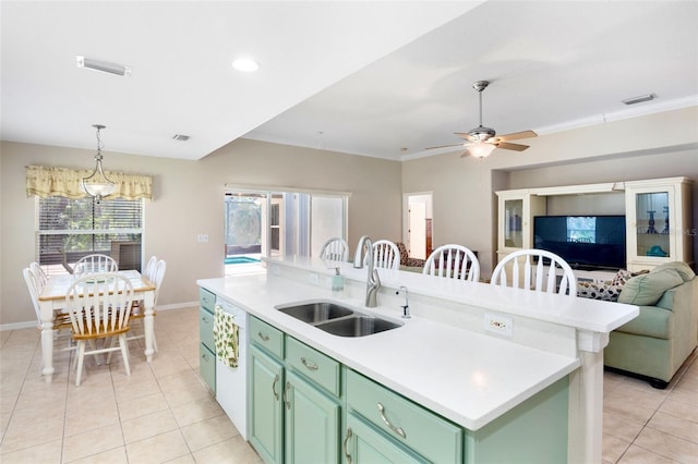 kitchen featuring sink, green cabinetry, light tile patterned floors, ornamental molding, and a kitchen island with sink