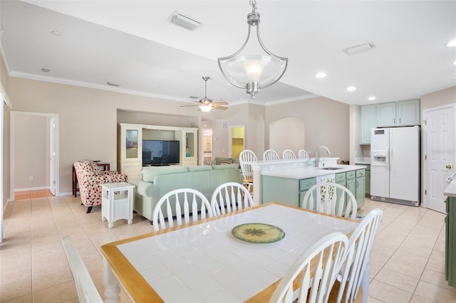 tiled dining room with ornamental molding, sink, and ceiling fan