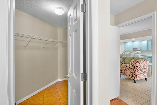 walk in closet with light tile patterned floors