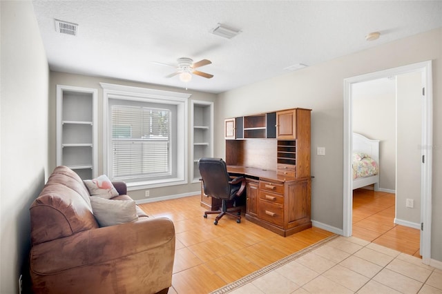 tiled office with ceiling fan, a textured ceiling, and built in shelves