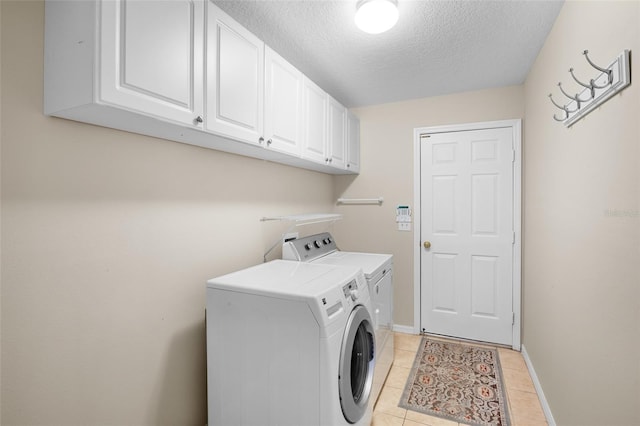 washroom with cabinets, light tile patterned floors, washer and dryer, and a textured ceiling