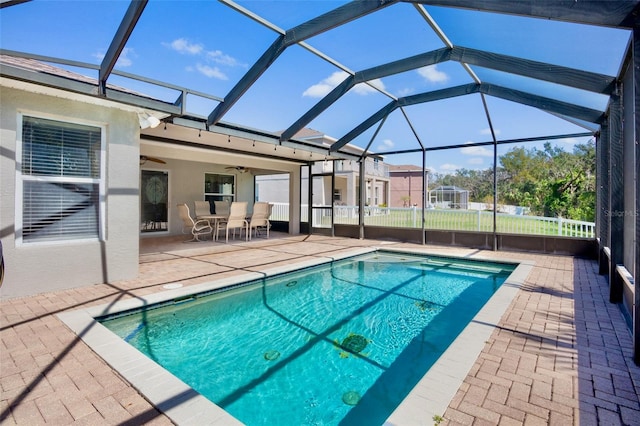 view of swimming pool featuring a patio, ceiling fan, and glass enclosure