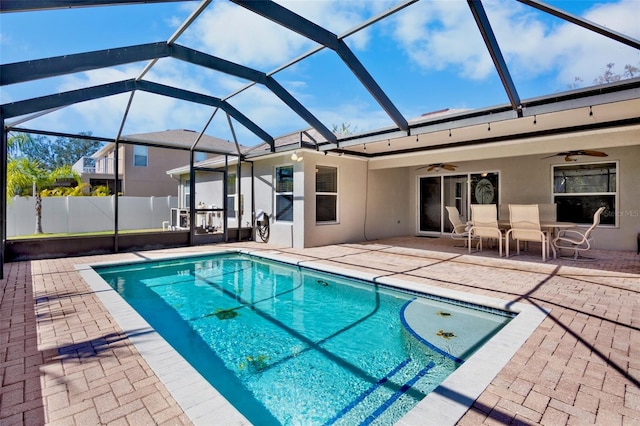 view of pool with a patio, ceiling fan, and glass enclosure