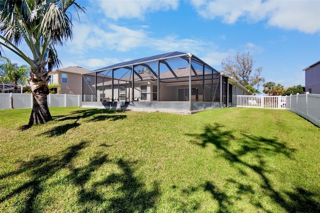 rear view of house featuring a yard and glass enclosure