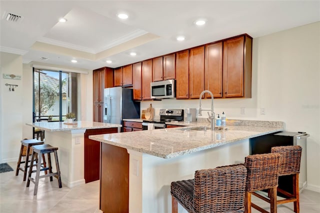 kitchen with light stone counters, stainless steel appliances, a breakfast bar, and kitchen peninsula