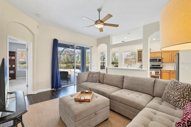 living room featuring ceiling fan, dark wood-type flooring, and a wealth of natural light