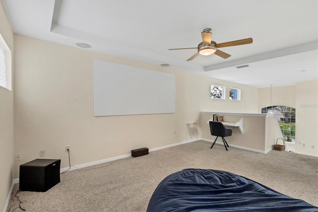 interior space with ceiling fan, a tray ceiling, and carpet flooring