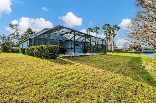 exterior space with glass enclosure, a lawn, and a water view