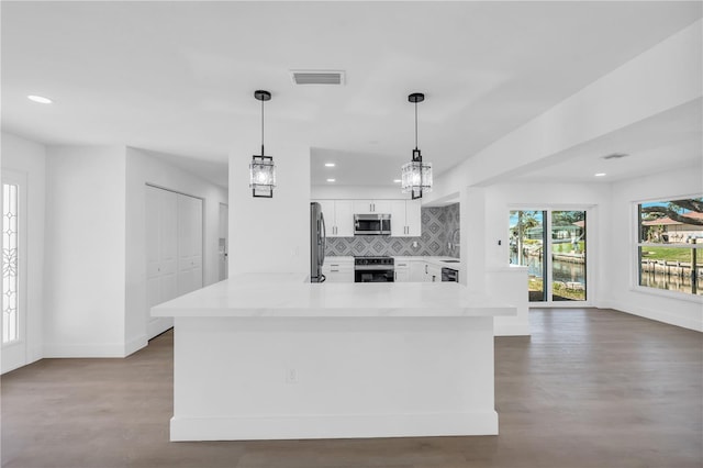 1950 Fairview Dr, Englewood, FL 34223 - kitchen featuring white cabinetry, backsplash, wood-type flooring, appliances with stainless steel finishes, and pendant lighting