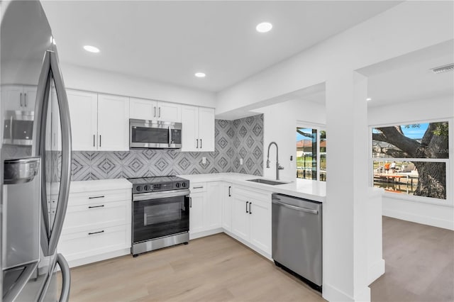 1950 Fairview Dr, Englewood, FL 34223 - kitchen featuring sink, stainless steel appliances, white cabinetry, and light hardwood / wood-style floors