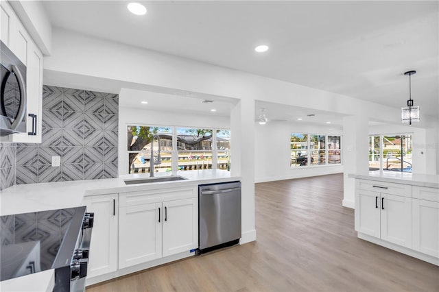 1950 Fairview Dr, Englewood, FL 34223 - kitchen with hanging light fixtures, stainless steel appliances, white cabinets, light hardwood / wood-style floors, and sink