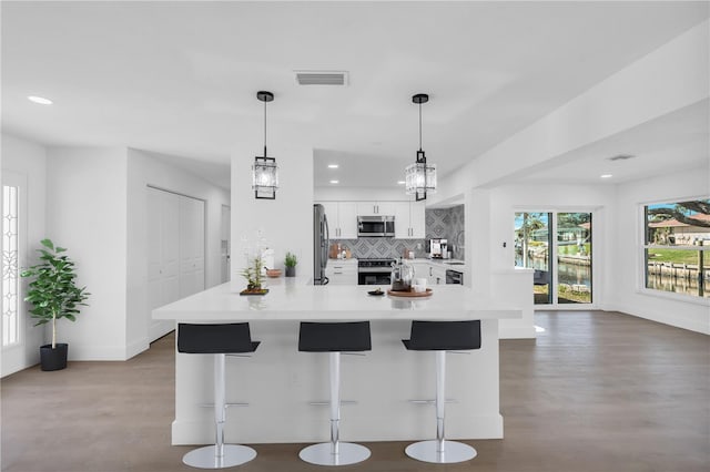 1950 Fairview Dr, Englewood, FL 34223 - kitchen featuring white cabinetry, a kitchen breakfast bar, stainless steel appliances, hanging light fixtures, and decorative backsplash