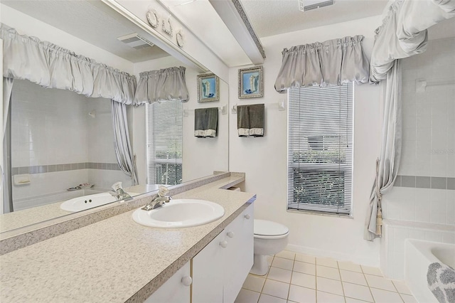 bathroom featuring a tub, tile patterned flooring, vanity, toilet, and a textured ceiling