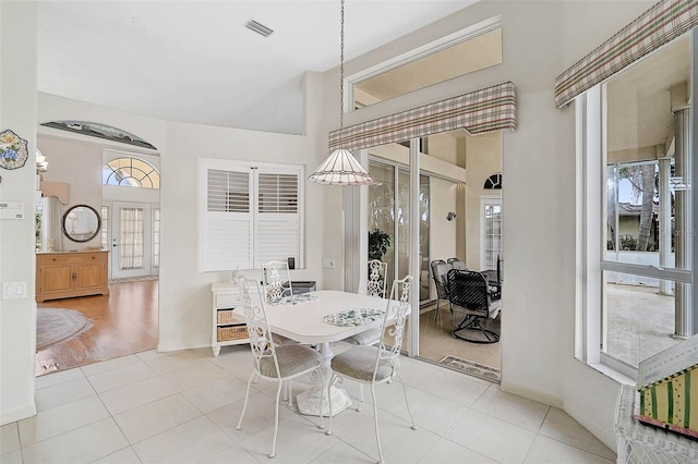 dining space featuring a towering ceiling and light tile patterned floors