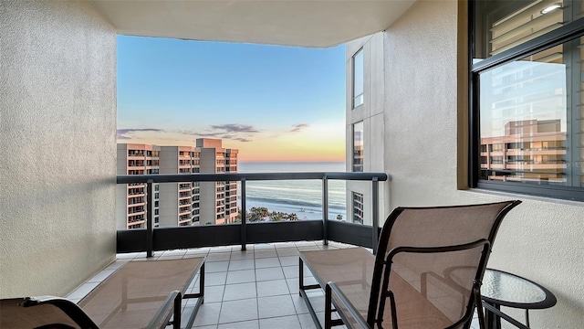 balcony at dusk featuring a water view