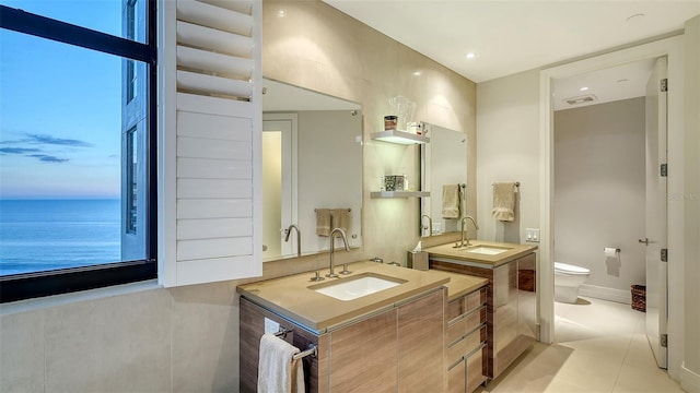 bathroom with a water view, vanity, toilet, and tile patterned flooring