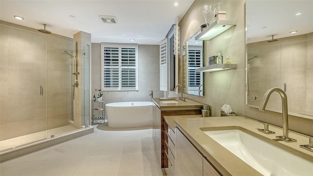 bathroom with vanity, independent shower and bath, tile patterned flooring, and tile walls