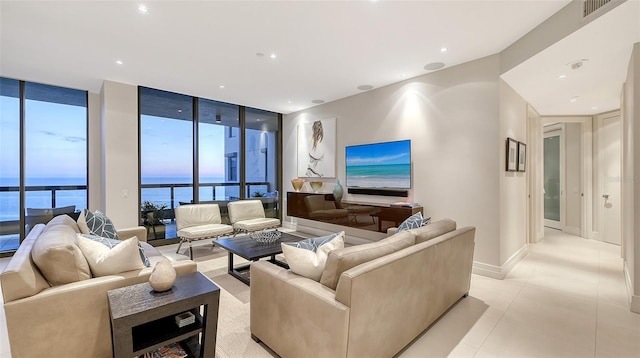 tiled living room featuring a wall of windows and a water view