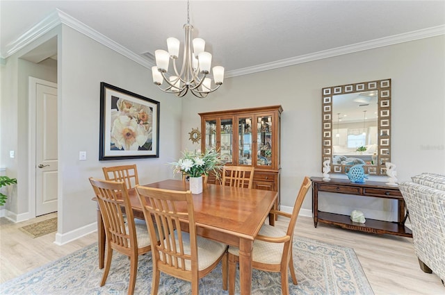 dining area with crown molding, light hardwood / wood-style flooring, and a notable chandelier