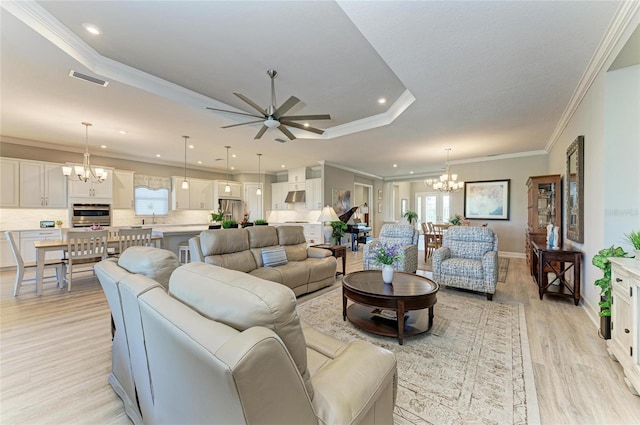 living room featuring ceiling fan with notable chandelier, ornamental molding, a raised ceiling, and light hardwood / wood-style floors