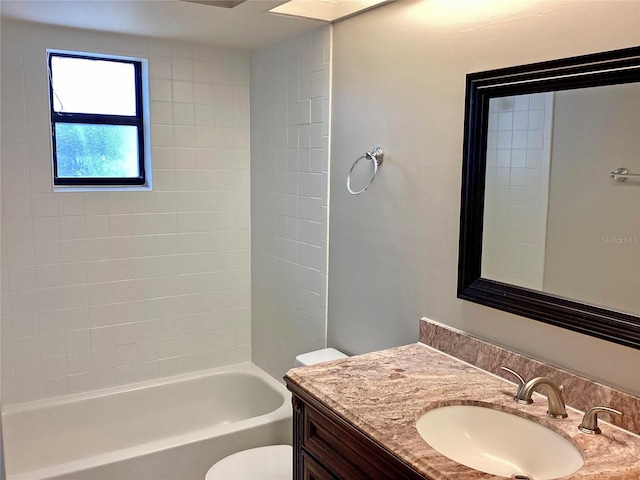 full bathroom with tiled shower / bath, vanity, and toilet