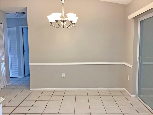 tiled spare room featuring a chandelier