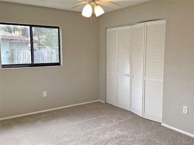 unfurnished bedroom with ceiling fan, a closet, a textured ceiling, and carpet flooring