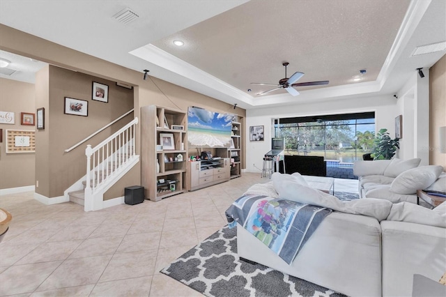 living room featuring light tile patterned floors, a raised ceiling, a textured ceiling, and ceiling fan