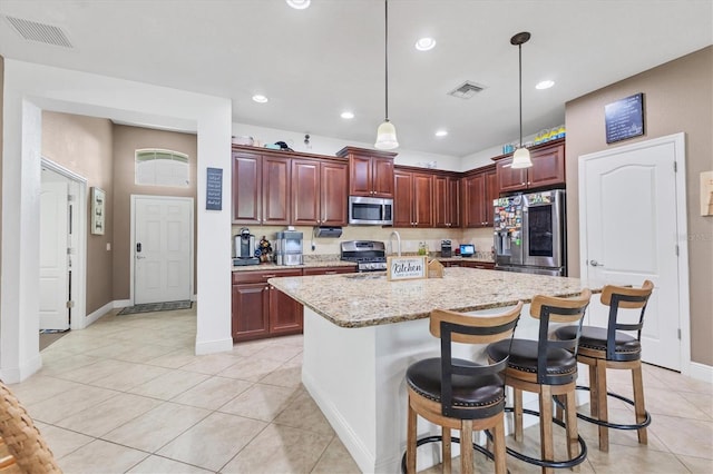 kitchen with a kitchen bar, light stone counters, decorative light fixtures, a kitchen island, and stainless steel appliances