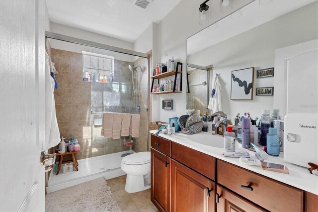 bathroom with tile patterned flooring, vanity, a shower with shower door, and toilet