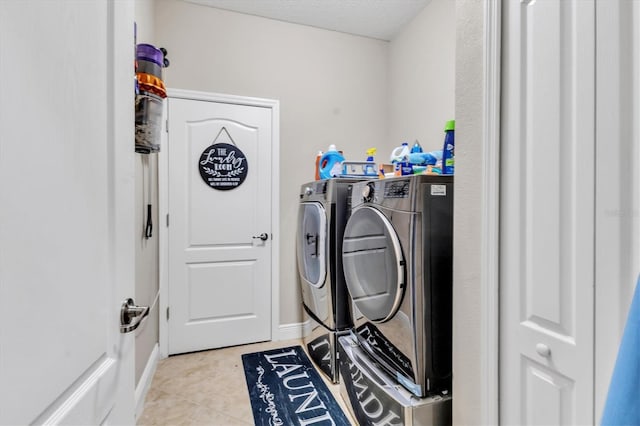 laundry area with washing machine and dryer, light tile patterned flooring, and a textured ceiling