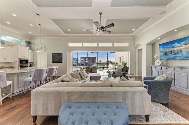 living room with crown molding, dark wood-type flooring, ceiling fan, and a towering ceiling