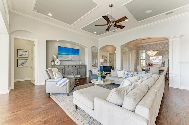 living room featuring ornate columns, dark hardwood / wood-style floors, ceiling fan with notable chandelier, coffered ceiling, and crown molding