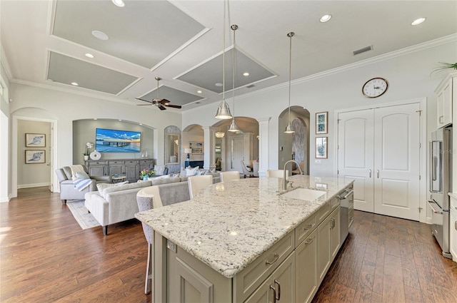 kitchen with pendant lighting, sink, appliances with stainless steel finishes, a kitchen breakfast bar, and a center island with sink