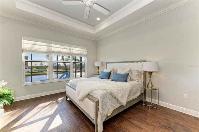 bedroom featuring crown molding, dark hardwood / wood-style floors, a raised ceiling, and a water view