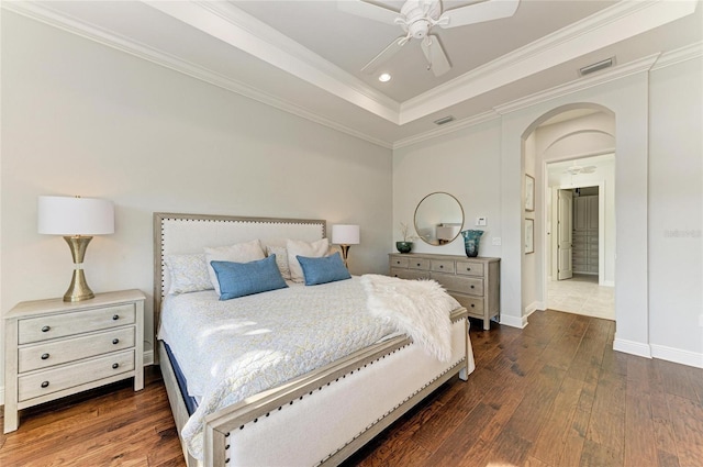 bedroom featuring a raised ceiling, crown molding, ceiling fan, and dark hardwood / wood-style flooring