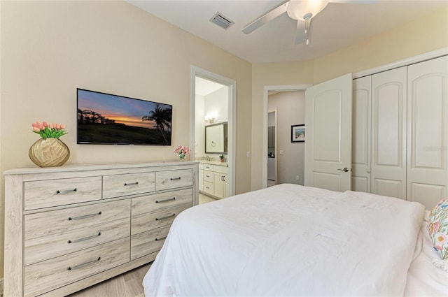 bedroom with connected bathroom, light hardwood / wood-style flooring, ceiling fan, and a closet