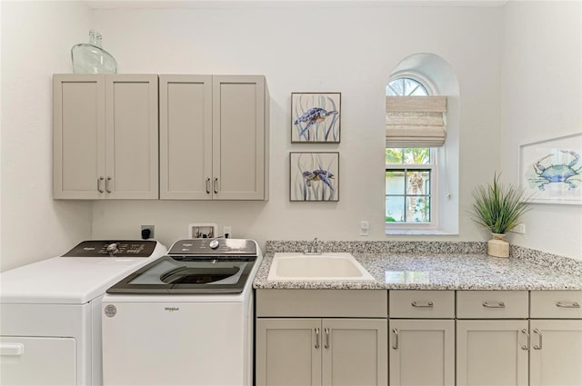 laundry area featuring cabinets, washing machine and clothes dryer, and sink