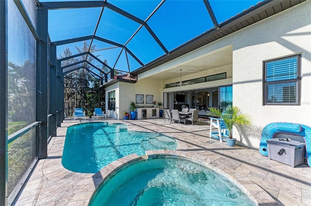 view of swimming pool featuring a patio, exterior kitchen, an in ground hot tub, a lanai, and ceiling fan